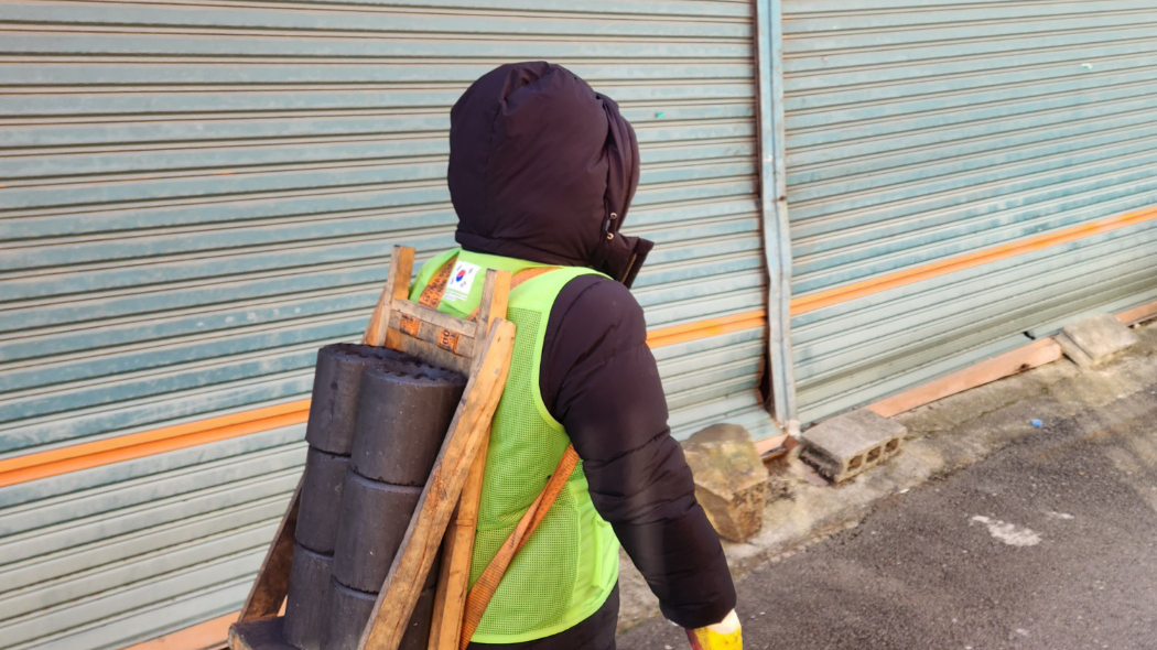 ▲사진: 희망조약돌 임직원이 연탄을 지게에 싣고 옮기고 있다. 출처: 희망조약돌